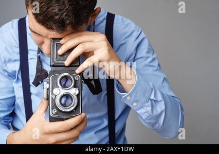 Guy mit der alten Kamera im Studio. Guy schießt auf eine alte Vintage-Filmkamera mit zwei Objektiven. Stockfoto