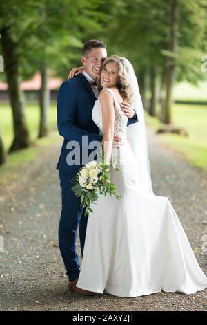 Brautpaar umarmte zärtlich beim Fotografieren im Park. Stockfoto