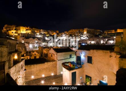 Späte Nacht Blick auf die beleuchtete antike sassi und die Häuser in der prähistorischen Stadt Matera, Italien, Teil der Region Basilikata und einer Unesco-Stätte. Stockfoto