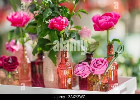 Frisch und dekorative künstliche Rosen in verschiedenen Vasen. Selektiver Fokus, getönt. Stockfoto
