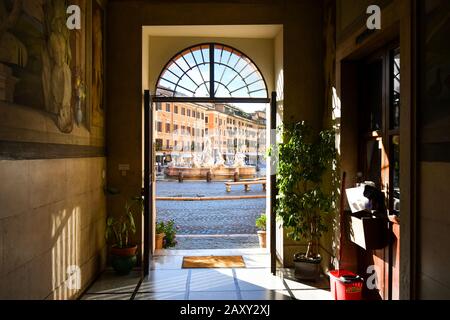 Blick auf den Neptun Brunnen mit Cafés hinter einer Tür eines mittelalterlichen Gebäudes auf der Piazza Navona in Rom, Italien Stockfoto