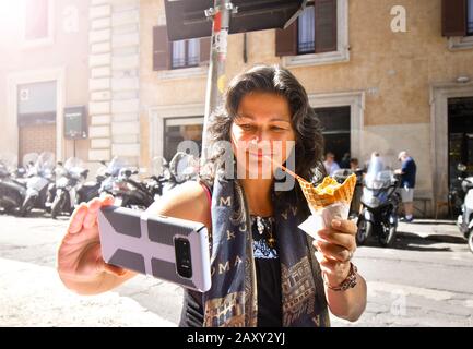 Eine kaukasische hispanische Frau nimmt beim Essen von Eisgelato in Rom, Italien, eine selfie. Stockfoto