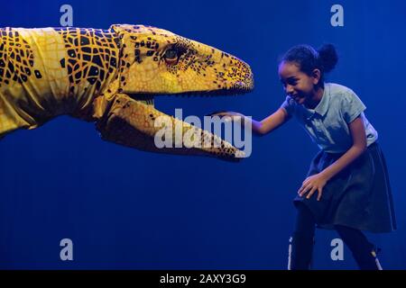 Kinder der Stockwell Primary School treffen lebensähnliche Dinosaurier-Marionetten, die derzeit im Erth's Dinosaur Zoo im Southbank Center, London, Großbritannien, erscheinen. Stockfoto