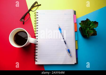 Draufsicht auf Notizblock und Kaffee auf Farbhintergrund Stockfoto