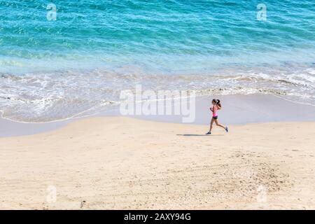 Läufer, der am Strand am Meer läuft - Blick von oben. Frau Athletin trainiert Cardio Jogging beim morgendlichen Workout. Hero Shot, viel Copyspace. Stockfoto