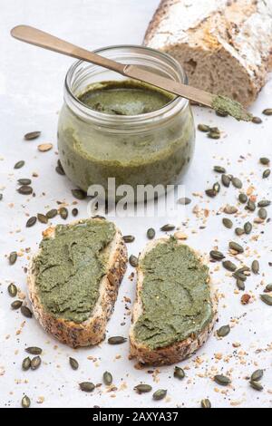 Hausgemachte vegane Kürbissaatbutter in einem kilner Glas und auf einem weißen Sauerteig Brot auf weißem Hintergrund Stockfoto