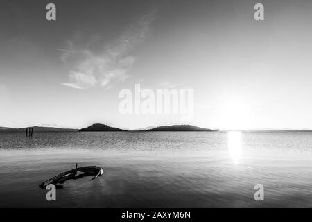 Ein leeres kleines Boot im Trasimeno-See (Umbrien, Italien) bei Sonnenuntergang Stockfoto