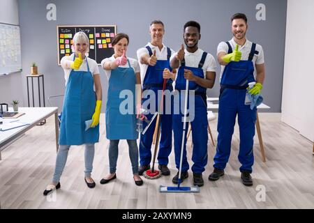 Portrait von Happy Diverse Hausmeister im Büro mit der Reinigung der Ausrüstung zeigen Daumen Anmelden Stockfoto