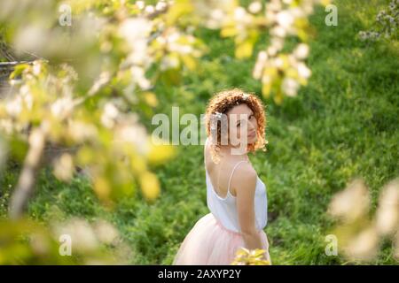 Junges attraktives Mädchen Spaziergänge in Spring Green Park genießen Sie blühende Natur. Gesunde lächelnde Mädchen auf der Feder Rasen drehen. Allergie ohne. Stockfoto