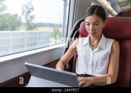 Geschäftsfrau, die mit dem Laptop im Zug arbeitet. Freiberuflicher asiatischer Autor oder Designer, der E-Mails auf dem Computer schreibt, während er zur Besprechung in der Stadt pendelt. Pendlerfrau im städtischen Reiseverkehr. Stockfoto