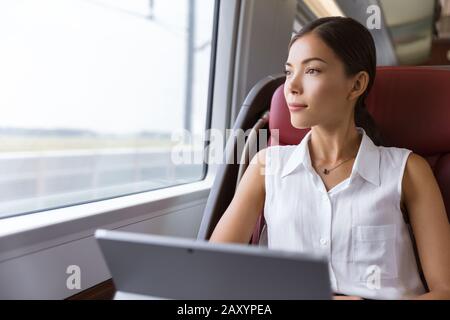 Asian Woman mit Laptop im Zug unterwegs. Geschäftsfrau, die auf dem Arbeitsweg auf dem Computer arbeitet, um das Fenster zu betrachten, ist bereit, auf die Arbeit zu gehen. Stockfoto