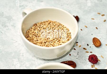 Rohes Haferflocken in einem Keramikbecher auf dem Tisch. Stockfoto