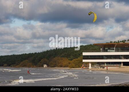 Tallinn, Estland - 18. Oktober 2008: Kitesurfer in einem roten Anzug reitet auf den Wellen des Meeres, das an einem Taumseil von einem Segel hält. Bewölkt und windig. B. Stockfoto