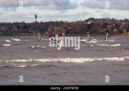 Tallinn, Estland - 18. Oktober 2008: Kitesurfer springt hoch über das Meer und macht Tricks mit hüpfenden im Wind. Viele verschwommene Windsurfer auf dem Stockfoto