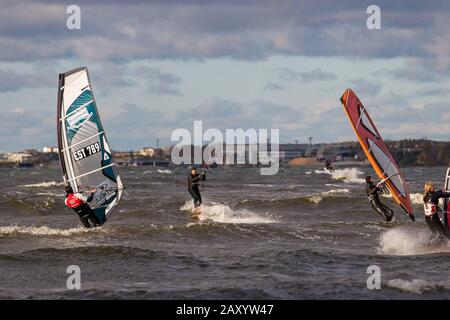 Tallinn, Estland - 18. Oktober 2008: Kitesurfer fahren zwischen Windsurfern auf den Wellen des Meeres. Bewölkt und windig. Verschwommener Hintergrund. Stockfoto