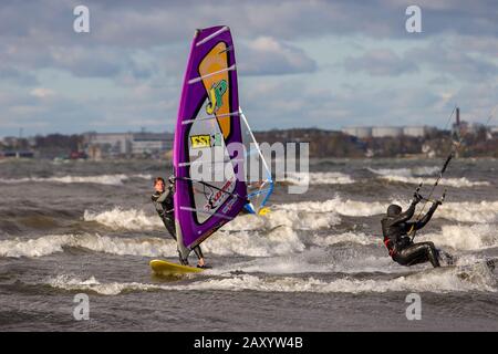 Tallinn, Estland - 18. Oktober 2008: Windsurfer und Kitesurfer in Schutzanzügen fahren auf den Wellen des Meeres. Bewölkt und windig. Verschwommenes Backgr Stockfoto