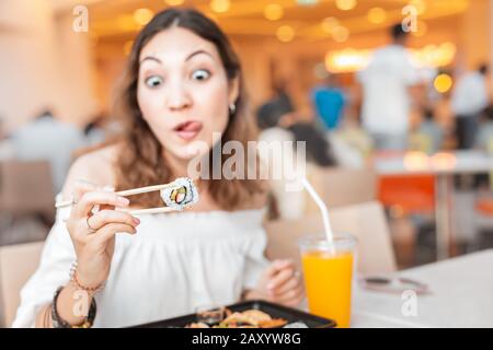 Funny Girl, das Sushi mit Essstäbchen isst, während er Bento auf dem Lebensmittelplatz zu Mittag essen hat Stockfoto