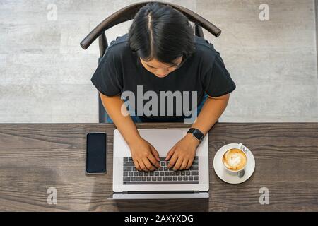 Overhead-Ansicht Foto der Frau, die mit einem Laptop in einer Kaffeemaschine arbeitet Stockfoto