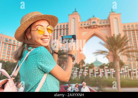 Fröhliche reisende asiatischer Mädchen, die Fotos von dem berühmten Luxushotel Atlantis auf einer Jumeirah Palm Island in Duba, VAE machen. Stockfoto
