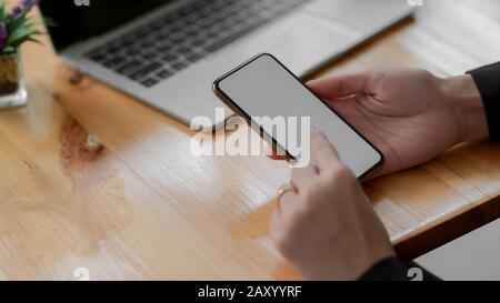 Zugeschnittene Aufnahme einer Frau mit leerem Bildschirm-Smartphone mit Laptop auf Holztischhintergrund Stockfoto