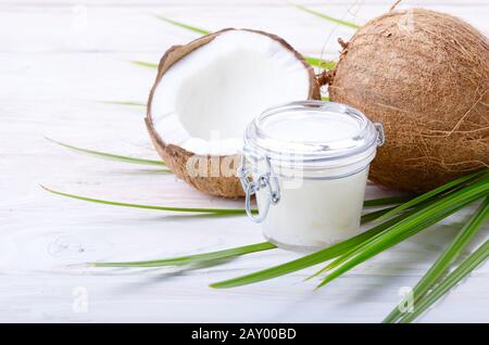 Kokosöl in luftdichten Glas Glas und Shell Stücke auf weiße Holztisch Stockfoto