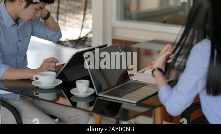Ein Schuss von zwei Geschäftsleuten, die sich auf ihre Arbeit mit einem Laptop konzentrieren, während sie sich gegenübersitzen Stockfoto
