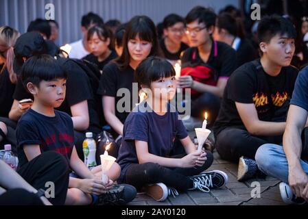 Hongkong, Hongkong SAR, China. Juni 2019. Protestierende halten eine Kerze, die Mahnwache in Erinnerung an "Regenmantel man", einen Demonstranten, der starb, als er versuchte, in der Nacht zuvor ein Protestbanner zu entfurchen.Der protestmarsch in Hongkong gegen den Auslieferungsentwurf von Hauptgeschäftsführer Carrie Lam endet damit, dass sich Demonstranten um die Regierungsgebäude und das Polizeihauptquartier versammeln. Die Aufhebung der Gesetzesvorlage unterbricht nicht den marsch, an dem schätzungsweise mehr als 2 Millionen Menschen teilnahmen. Credit: Jayne Russell/ZUMA Wire/Alamy Live News Stockfoto