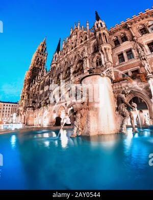 Nächtlicher Blick auf Fischbrunnen und beleuchtetes Gebäude des neuen Rathauses. Tourismus und Reisen nach Deutschland Konzept Stockfoto