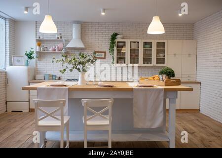 Moderne weiße Küche im skandinavischen Stil. Offene Regale in der Küche mit Pflanzen und Gläsern Stockfoto