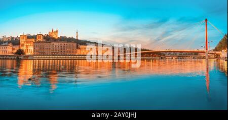 Stadtbild der Nacht von Lyon mit beleuchtetem Courthouse und roter Fußgängerbrücke über den Fluss Saone. Panorama-Blau-Stundenlandschaft Stockfoto