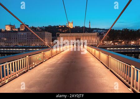 23. Juli 2019, Lyon, Frankreich: Stadtbild der Nacht von Lyon mit beleuchtetem Courthouse und roter Fußgängerbrücke über den Fluss Saone. Panorama-Blau-Stundenlandschaft Stockfoto