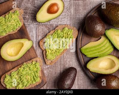 Blick auf gesunde Sandwiches, die mit Avocado auf einem Holzbrett zubereitet werden Stockfoto