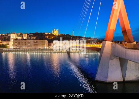 23. Juli 2019, Lyon, Frankreich: Stadtbild der Nacht von Lyon mit beleuchtetem Courthouse und roter Fußgängerbrücke über den Fluss Saone. Panorama-Blau-Stundenlandschaft Stockfoto