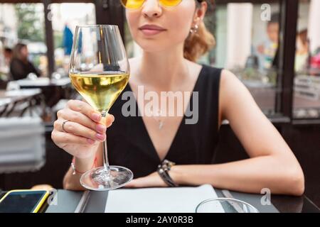 Junge asiatische Kundin trinkt Weißwein Stockfoto