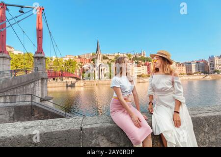 Zwei glückliche Mädchen-Freunde, die auf der Fußgängerbrücke Saint Georges spazieren gehen, während sie in der französischen Altstadt von Lyon unterwegs sind Stockfoto