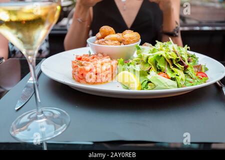 Gericht mit Lachsfilet und Grüns mit Wein im Restaurant Stockfoto