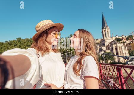 Zwei glückliche Mädchen-Freunde, die auf der Fußgängerbrücke Saint Georges spazieren gehen, während sie in der französischen Altstadt von Lyon unterwegs sind Stockfoto