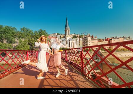 Zwei glückliche Mixed-Race-Mädchen, die Spaß haben und auf einer Brücke springen, während sie in der französischen Stadt Lyon unterwegs sind Stockfoto