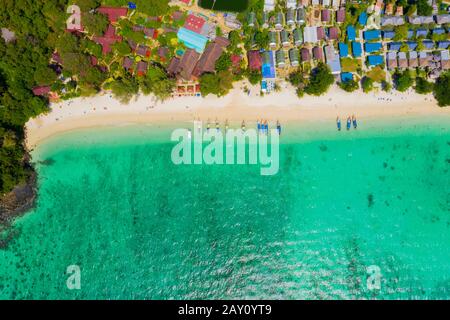 Blick von oben, atemberaubender Luftblick auf einen schönen tropischen Strand mit weißem Sand und türkisfarbenem klarem Wasser, Langschwänzboot und Menschen zum Sonnenbaden, Lo Stockfoto