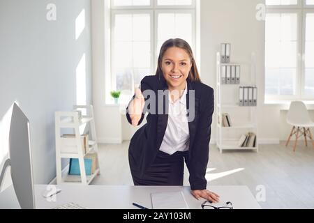 Handshake offering.Smiling Female Businessman macht ein Handshake-Angebot an einem Tisch im Büro. Stockfoto