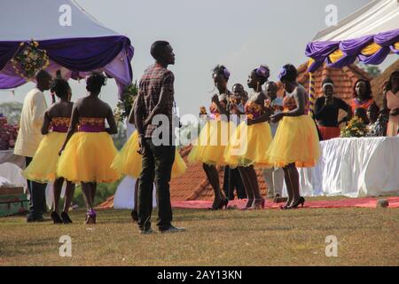 Kampala, Uganda - 24. Januar 2015: Afrikanische Hochzeitsfeier im Park mit schönen Mädchen, die in traditionellen Kleidern mit gelben Röcken und dem l tanzen Stockfoto