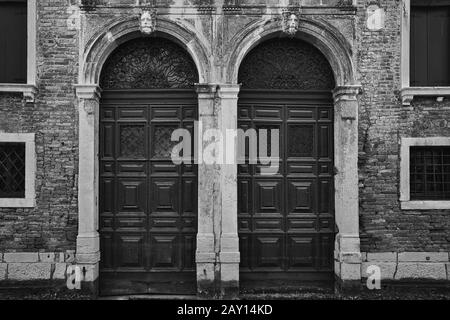 Venedig, ITALIEN - 20. Februar 2019: Ein Graustufenschuss eines alten Gebäudes mit Türen zu den Bögen in Venedig, Italien Stockfoto