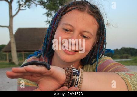 Das plump junge weiße Mädchen, das der Reisende mit Haaren in blauen Schwänzen hat, hält einen Wurm Julida an der Hand Stockfoto