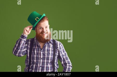 Glücklicher St. Patricks Tag. Fetter lustiger Mann in einem grünen Hut lächelt auf einem grünen Hintergrund Patricks Day. Stockfoto