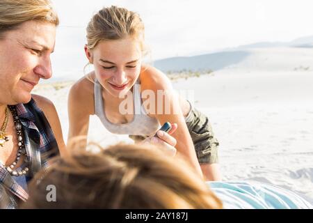 Mutter, die ihr Smartphone ansieht, während ihre Kinder zusehen Stockfoto