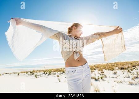 13 Jahre altes Mädchen tanzt mit einer Schal auf der Freifläche weißer Sanddünen. Stockfoto