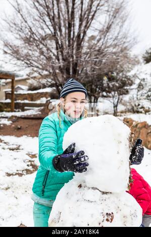 Dreizehnjähriges Mädchen im Teenager-Alter, das einen Schneemann baut Stockfoto