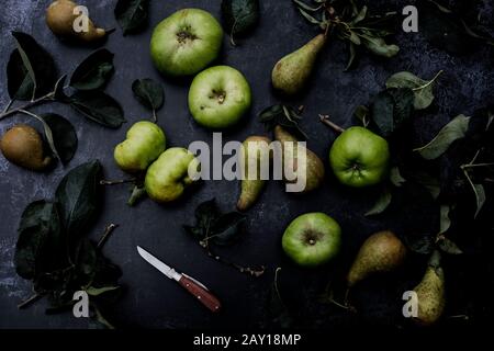 Hochwinkelige Nahaufnahme von grünen Birnen und Bramley-Äpfeln auf schwarzem Grund. Stockfoto