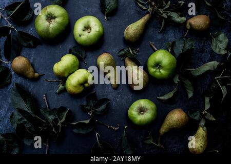 Hochwinkelige Nahaufnahme von grünen Birnen und Bramley-Äpfeln auf schwarzem Grund. Stockfoto