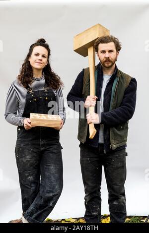 Porträt der Frau und bärtiger Mann, der Holzblöcke vor weißem Hintergrund hält und die Kamera betrachtet. Stockfoto